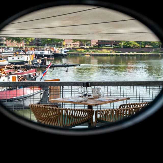 Door het ronde raampje… een blik op de haven. ⛵ Een uitzicht dat nooit verveelt tijdens je lunch of diner. 😉